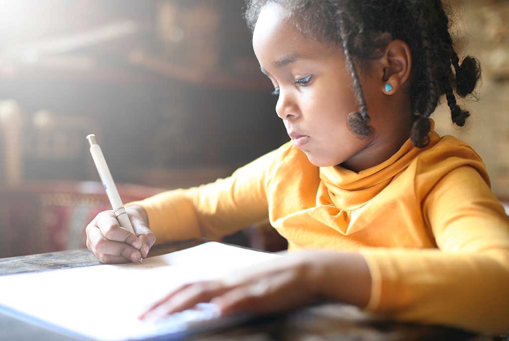 School child. African American girl writing in notebook.