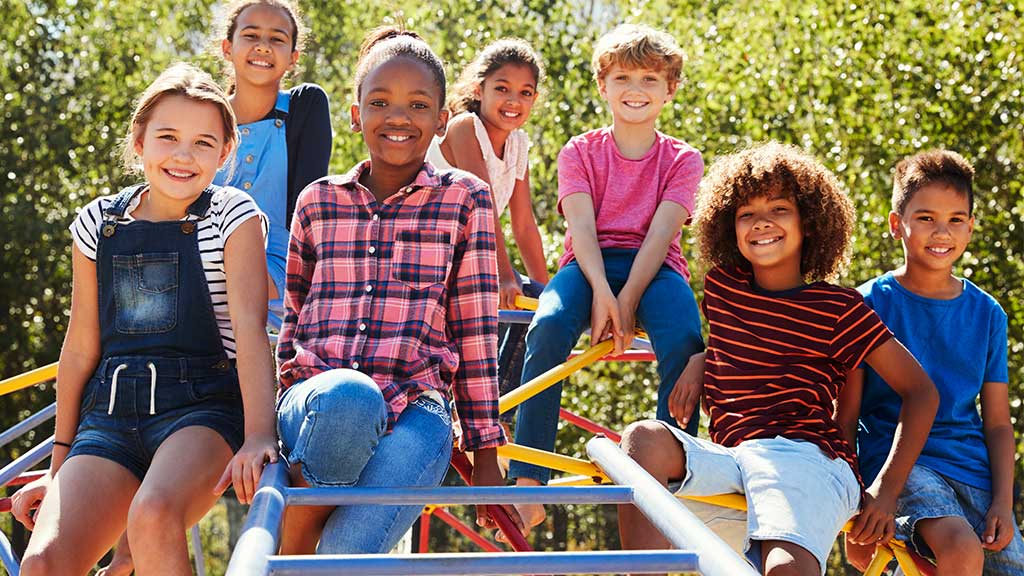 Pre-teen friends sitting on climbing frame in playground