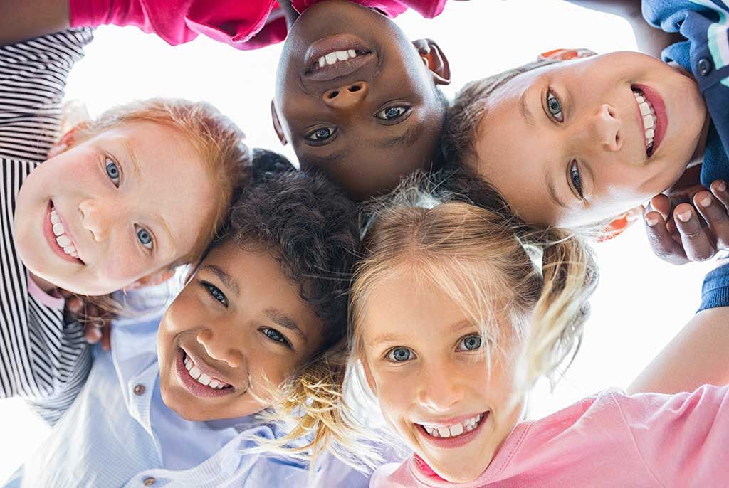 Closeup face of happy multiethnic children embracing each other and smiling at camera.